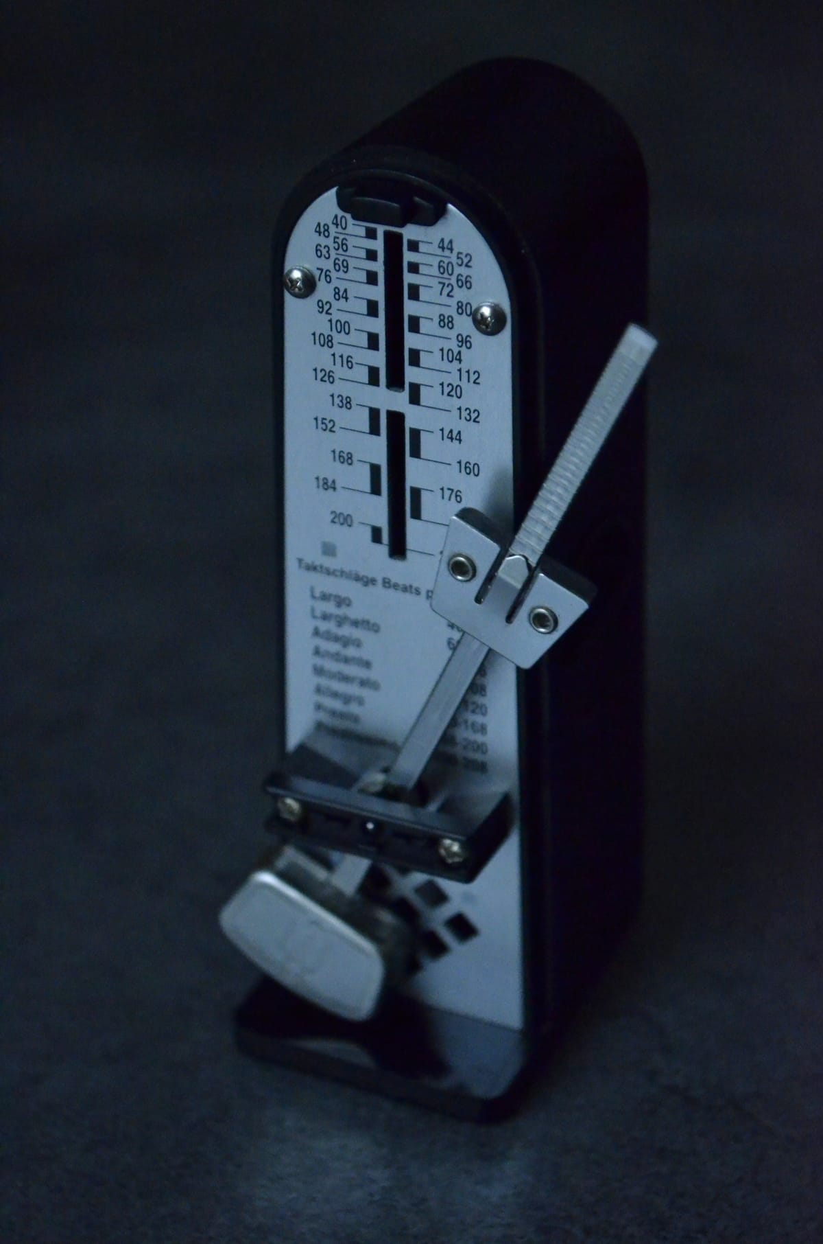 Mechanical metronome on a plain dark surface, suggesting timing and planning